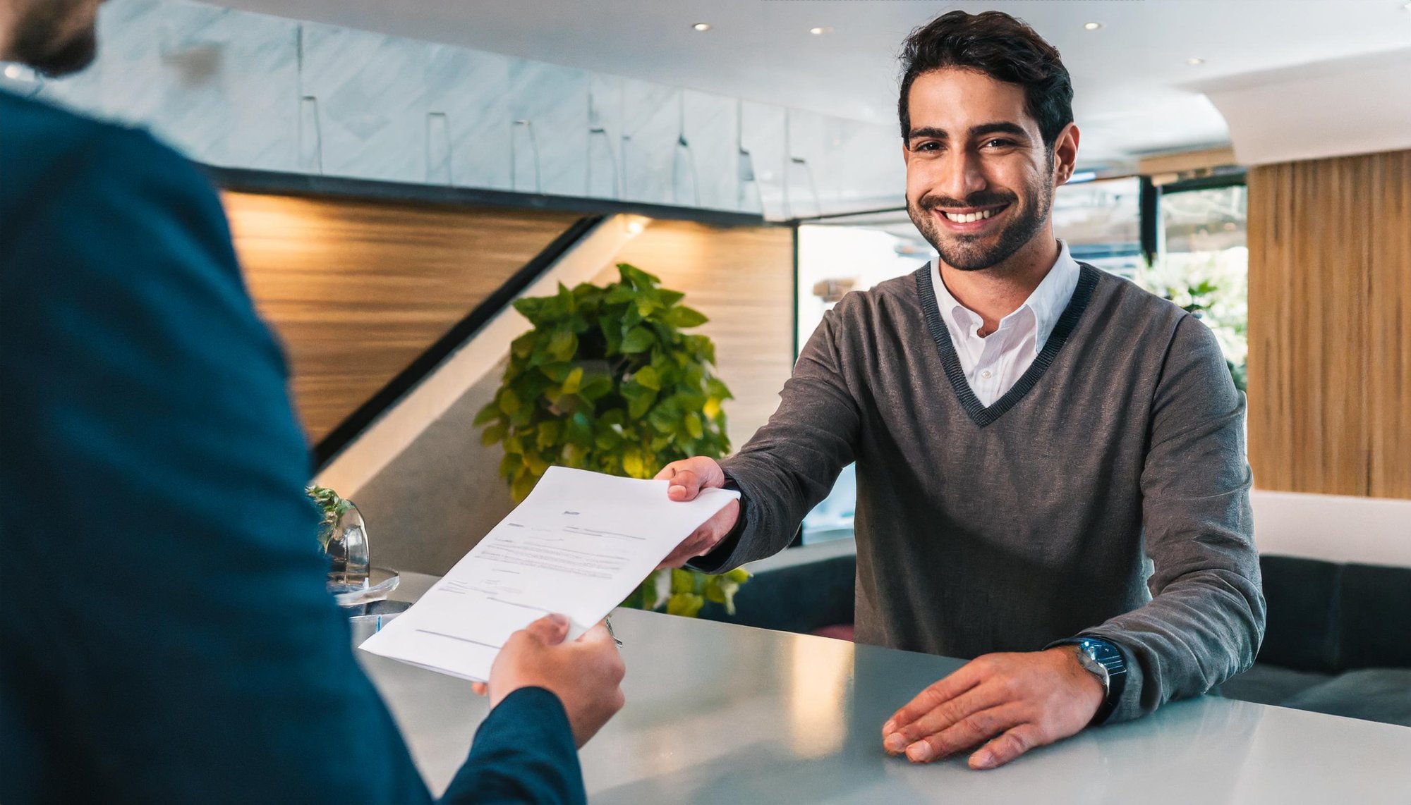 Firefly hospitality environment- a man behind the desk is handing an invoice for services to a custo